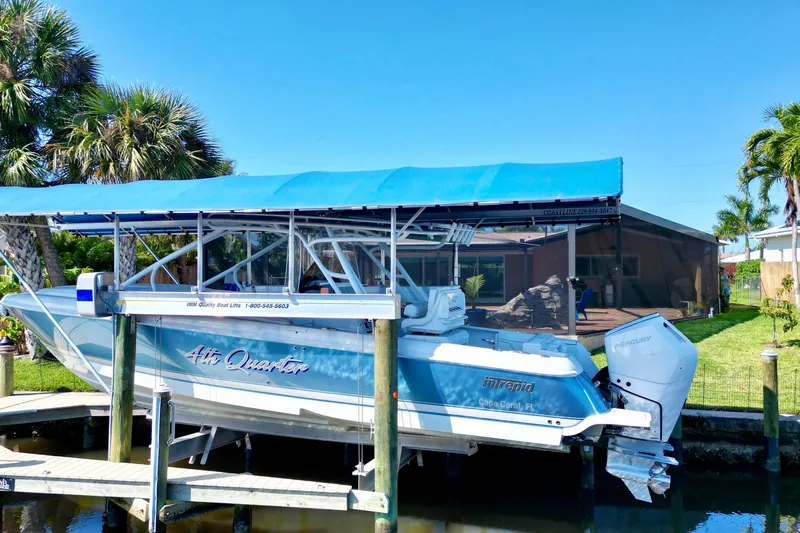  Yacht Photos Pics 2025 Intrepid 327 Cuddy boat docked with blue canopy, surrounded by palm trees.