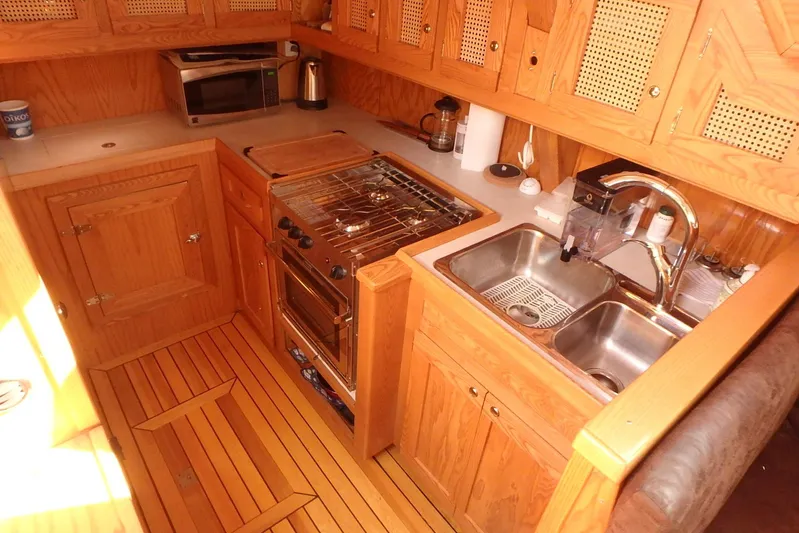 Si J'avais Su Yacht Photos Pics Wooden yacht kitchen with stove, double sink, and microwave in a 2017 Gilbert Caroff Lex Eterna 47.