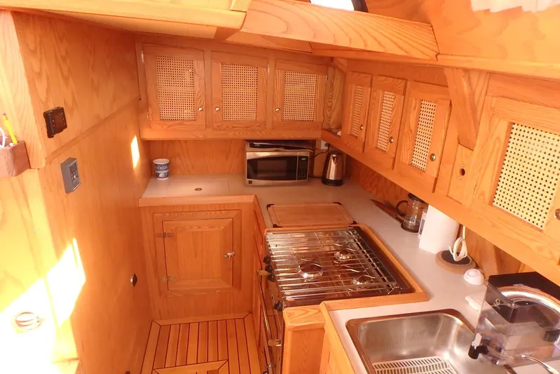 Si J'avais Su Yacht Photos Pics Wooden yacht kitchen interior with stove, sink, and cabinets in a 2017 Gilbert Caroff Lex Eterna 47.