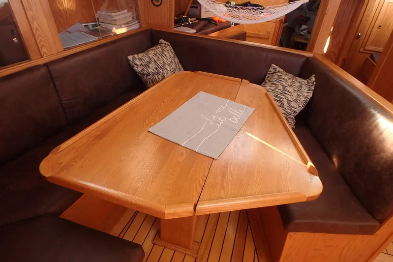 Si J'avais Su Yacht Photos Pics Cozy dining area on 2017 Custom Gilbert Caroff Lex Eterna 47 yacht with wooden table and cushions.