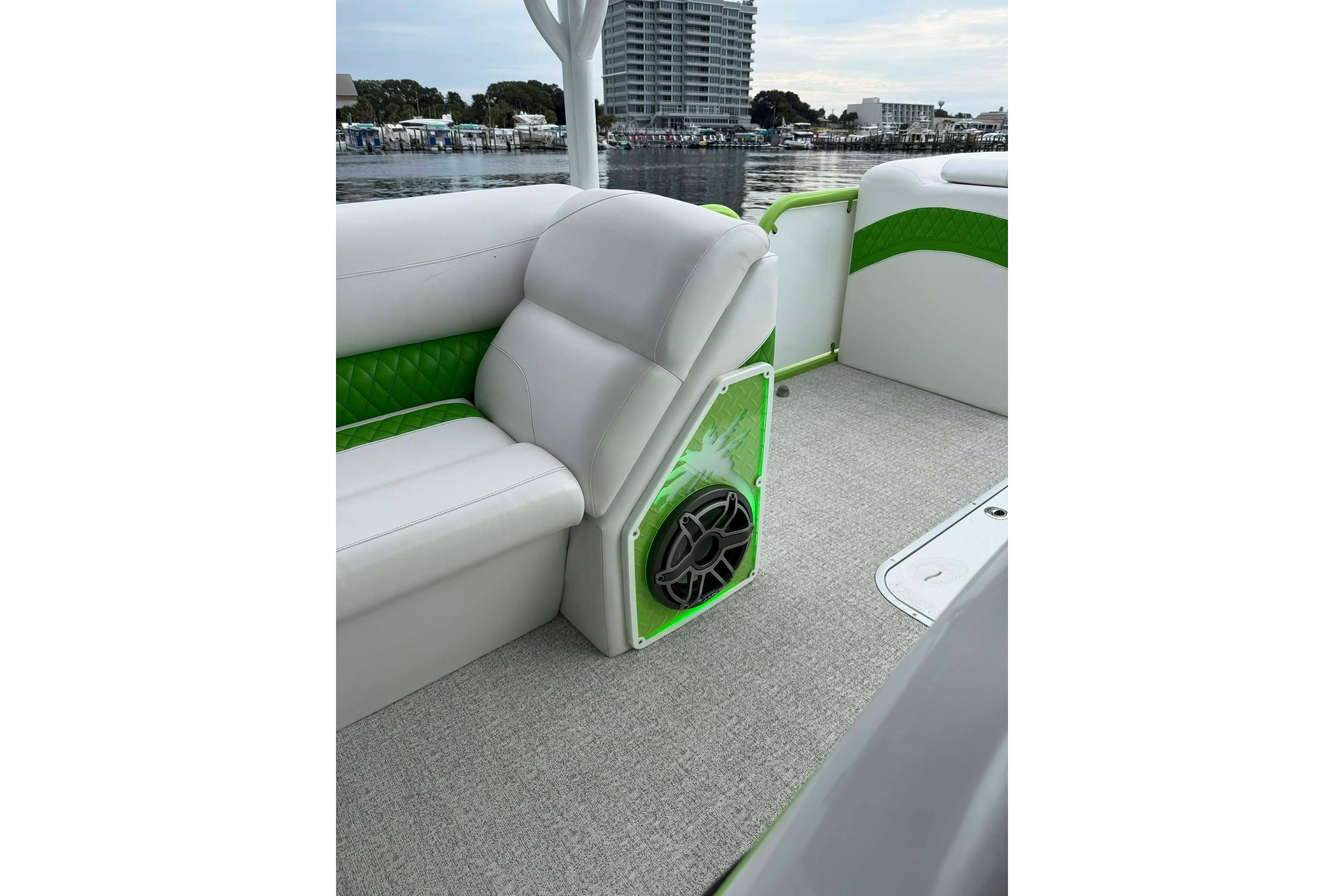 2026 Aloha Pontoon 300 interior with white and green seating, speaker, and waterfront view.