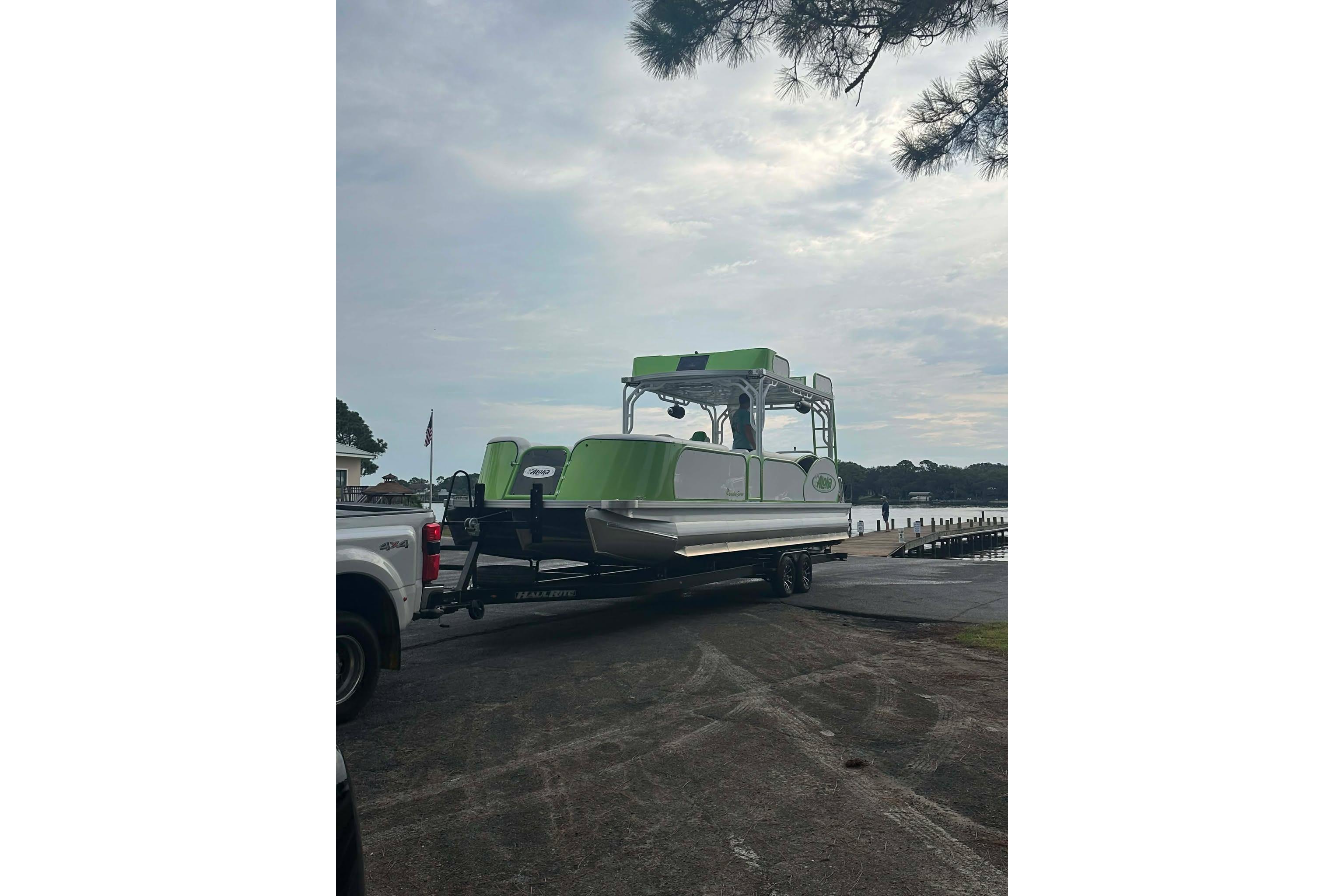 2026 Aloha Pontoon 300 on trailer near a lake, ready for launch.