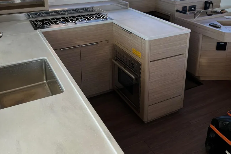 Aura Yacht Photos Pics Modern kitchen interior of 2024 Lagoon 46 yacht with stove and sink.