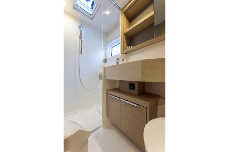 Aura Yacht Photos Pics Modern bathroom interior of 2024 Lagoon 46 yacht, featuring sleek shower and wooden cabinetry.