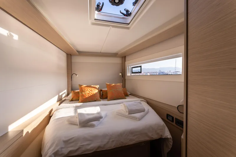 Aura Yacht Photos Pics Luxurious cabin interior of 2024 Lagoon 46 yacht with cozy bedding and natural light.