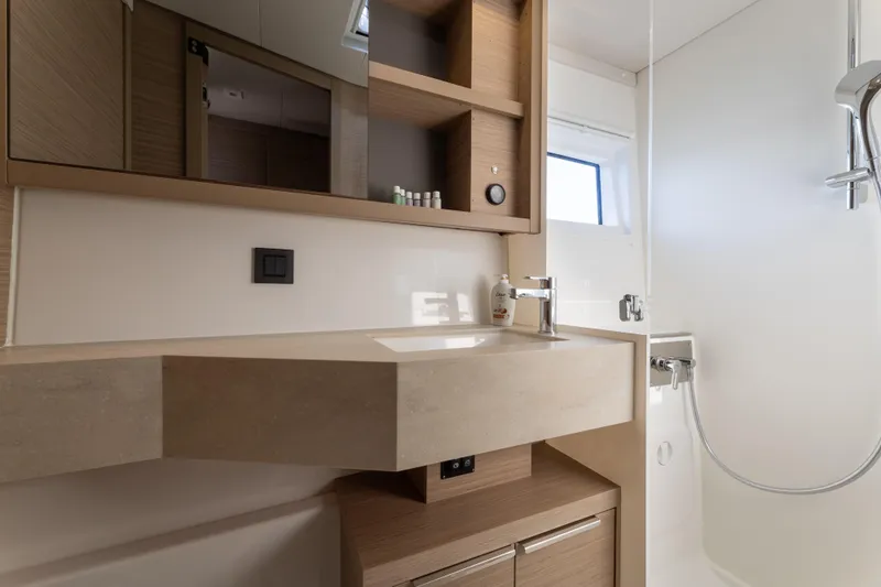 Aura Yacht Photos Pics Modern bathroom in 2024 Lagoon 46 yacht with sleek fixtures and wooden cabinetry.