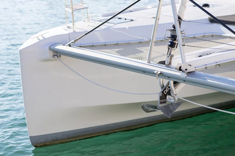 Aura Yacht Photos Pics 2024 Lagoon 46 catamaran bow with anchor, floating on clear blue water.