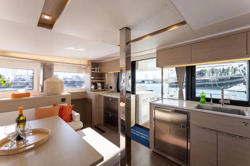 Aura Yacht Photos Pics Luxurious interior of 2024 Lagoon 46 yacht with modern kitchen and dining area.