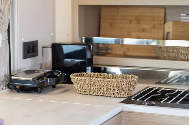 Aura Yacht Photos Pics Modern kitchen interior in 2024 Lagoon 46 yacht with appliances and woven basket.