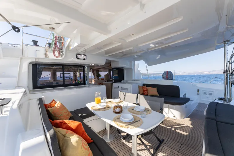 Aura Yacht Photos Pics Luxurious 2024 Lagoon 46 catamaran with elegant outdoor dining area and ocean view.