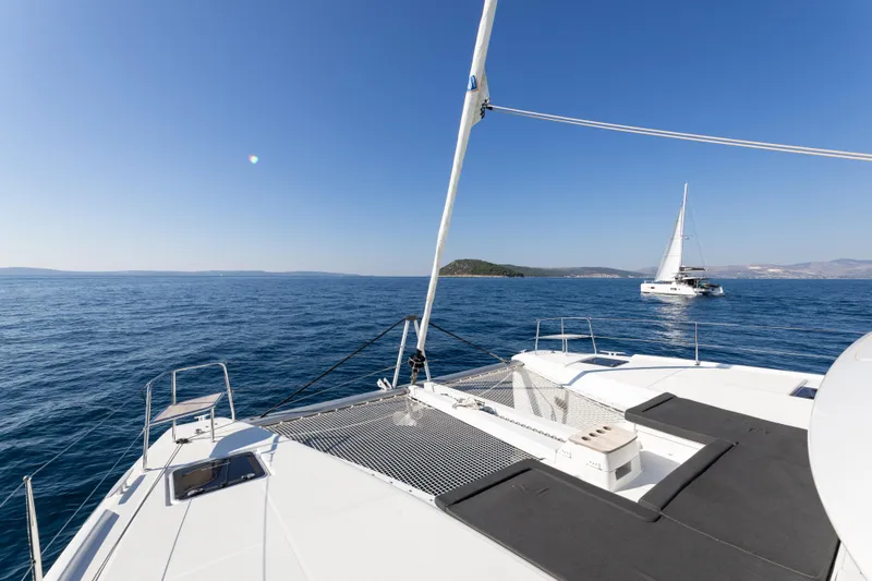 Aura Yacht Photos Pics 2024 Lagoon 46 catamaran sailing on open sea under clear blue sky.