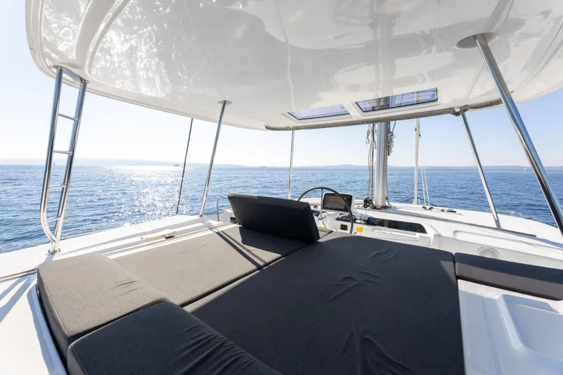 Aura Yacht Photos Pics 2024 Lagoon 46 catamaran deck with sunbathing area, overlooking serene ocean waters.