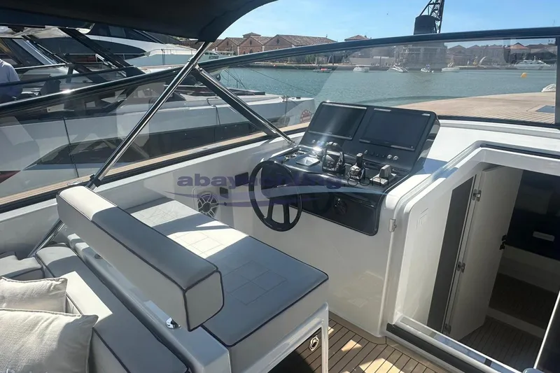  Yacht Photos Pics 2024 VanDutch 48 yacht cockpit with modern controls and seating, docked by the water.