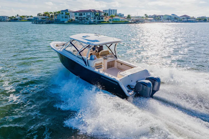  Yacht Photos Pics 2013 Grady-White Freedom 335 boat cruising on sunny waters near coastal homes.