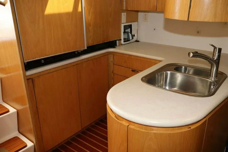  Yacht Photos Pics 2001 Tiara Yachts 4300 Open kitchen with wooden cabinetry and stainless steel sink.