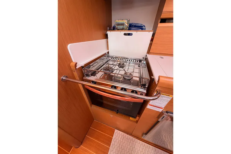 Joie Yacht Photos Pics 2011 Jeanneau 53 yacht kitchen with stove and oven, wooden cabinetry, and modern design.