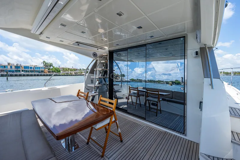  Yacht Photos Pics Luxurious 2014 Prestige 550 yacht deck with wooden table and chairs, overlooking serene waters.