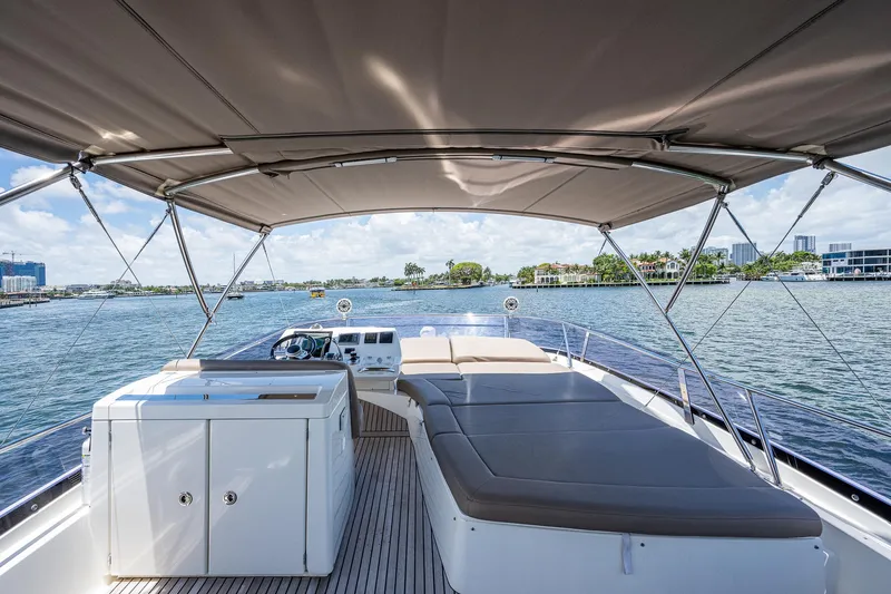  Yacht Photos Pics 2014 Prestige 550 yacht deck with sunbed and canopy on a scenic waterway.