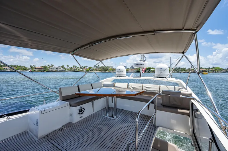  Yacht Photos Pics Luxurious 2014 Prestige 550 yacht deck with seating, table, and canopy on a sunny day.