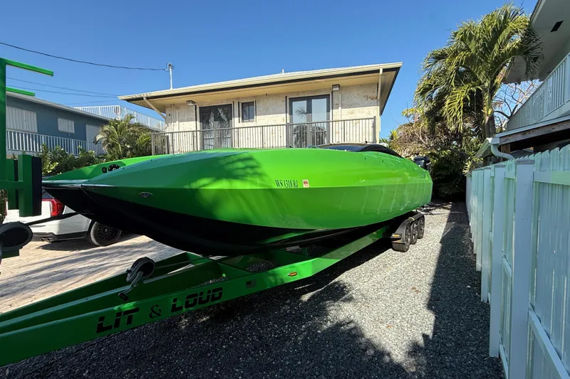 Yacht Photos Pics Green 2021 E-Ticket 29 boat on trailer, parked near a house with palm trees.