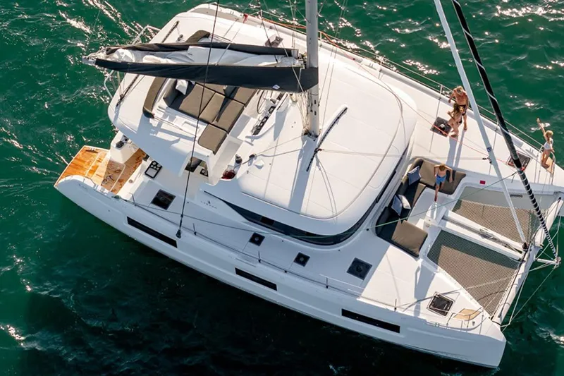  Yacht Photos Pics 2021 Lagoon 46 catamaran sailing on open water, featuring spacious deck and lounging area.