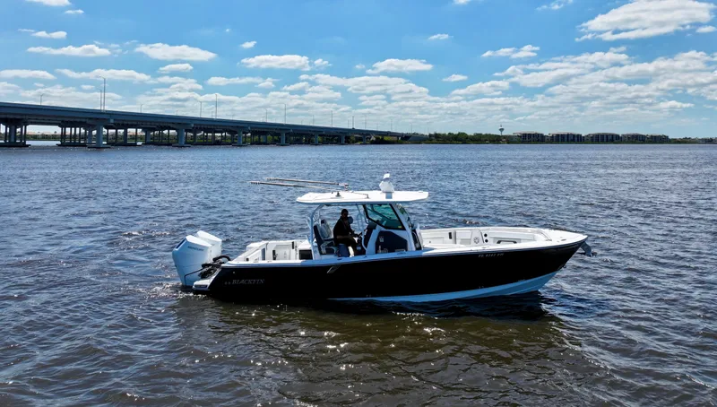 Yacht Photos Pics 2024 Blackfin 332 CC boat cruising on a sunny day near a bridge.