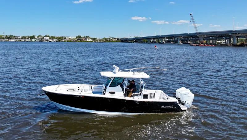  Yacht Photos Pics 2024 Blackfin 332 CC boat cruising on a sunny day near a bridge.