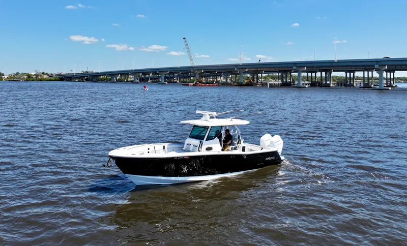  Yacht Photos Pics 2024 Blackfin 332 CC boat cruising on a sunny day near a bridge.