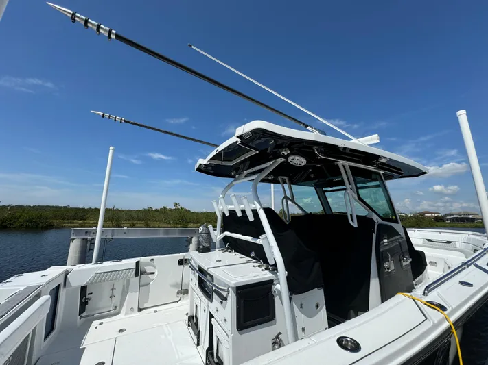  Yacht Photos Pics 2024 Blackfin 332 CC boat with fishing rods, docked under clear blue sky.