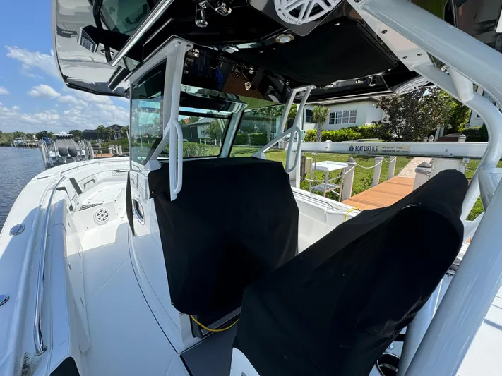  Yacht Photos Pics 2024 Blackfin 332 CC boat with covered seats, docked by a waterfront home.