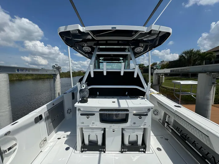  Yacht Photos Pics 2024 Blackfin 332 CC boat interior with seating and storage, docked under a clear sky.