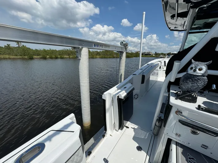  Yacht Photos Pics 2024 Blackfin 332 CC boat docked by a calm river under a partly cloudy sky.