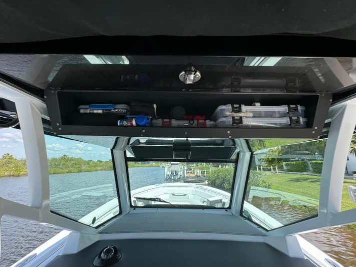  Yacht Photos Pics 2024 Blackfin 332 CC boat interior with storage compartment and scenic waterway view.