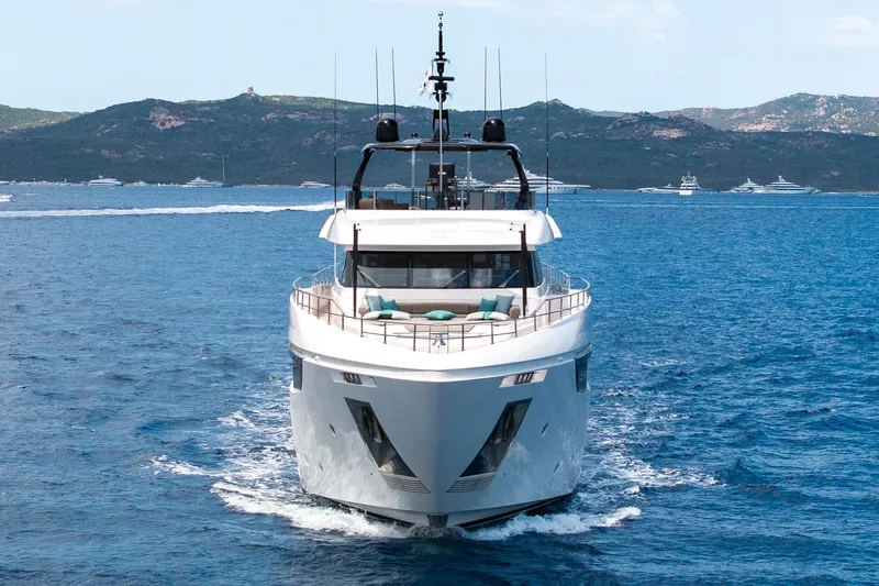 Queen J III Yacht Photos Pics 2024 Custom Line Navetta 33 yacht cruising on blue ocean with scenic mountain backdrop.