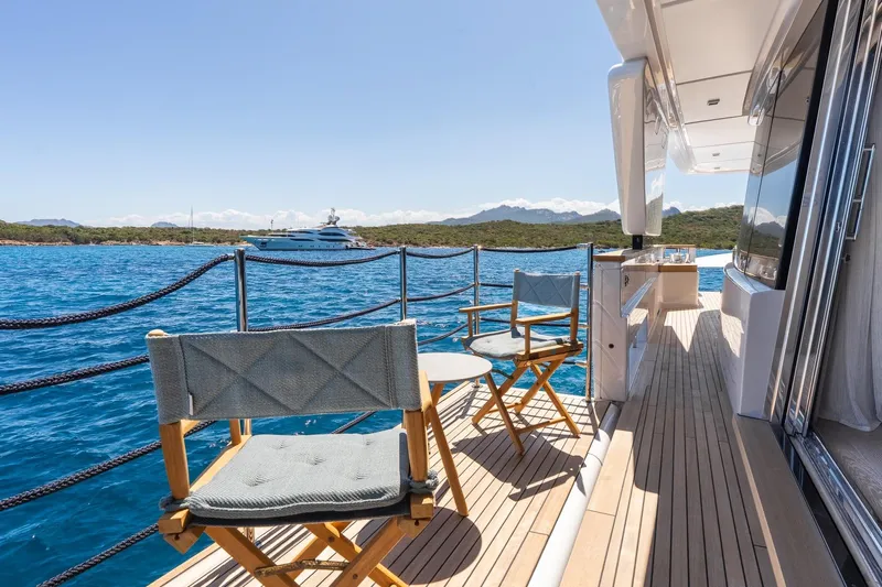 Queen J III Yacht Photos Pics Luxurious 2024 Custom Line Navetta 33 yacht deck with chairs, overlooking serene blue waters.