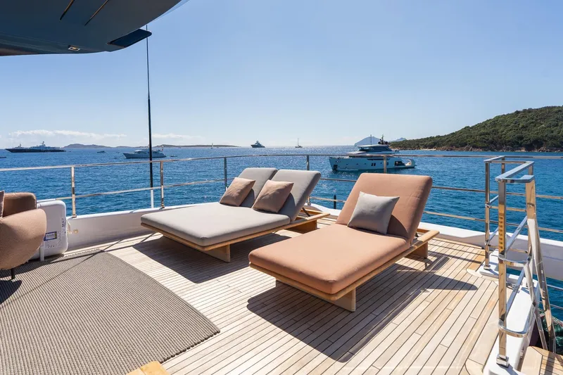 Queen J III Yacht Photos Pics Luxurious 2024 Custom Line Navetta 33 yacht deck with sun loungers, overlooking serene ocean view.