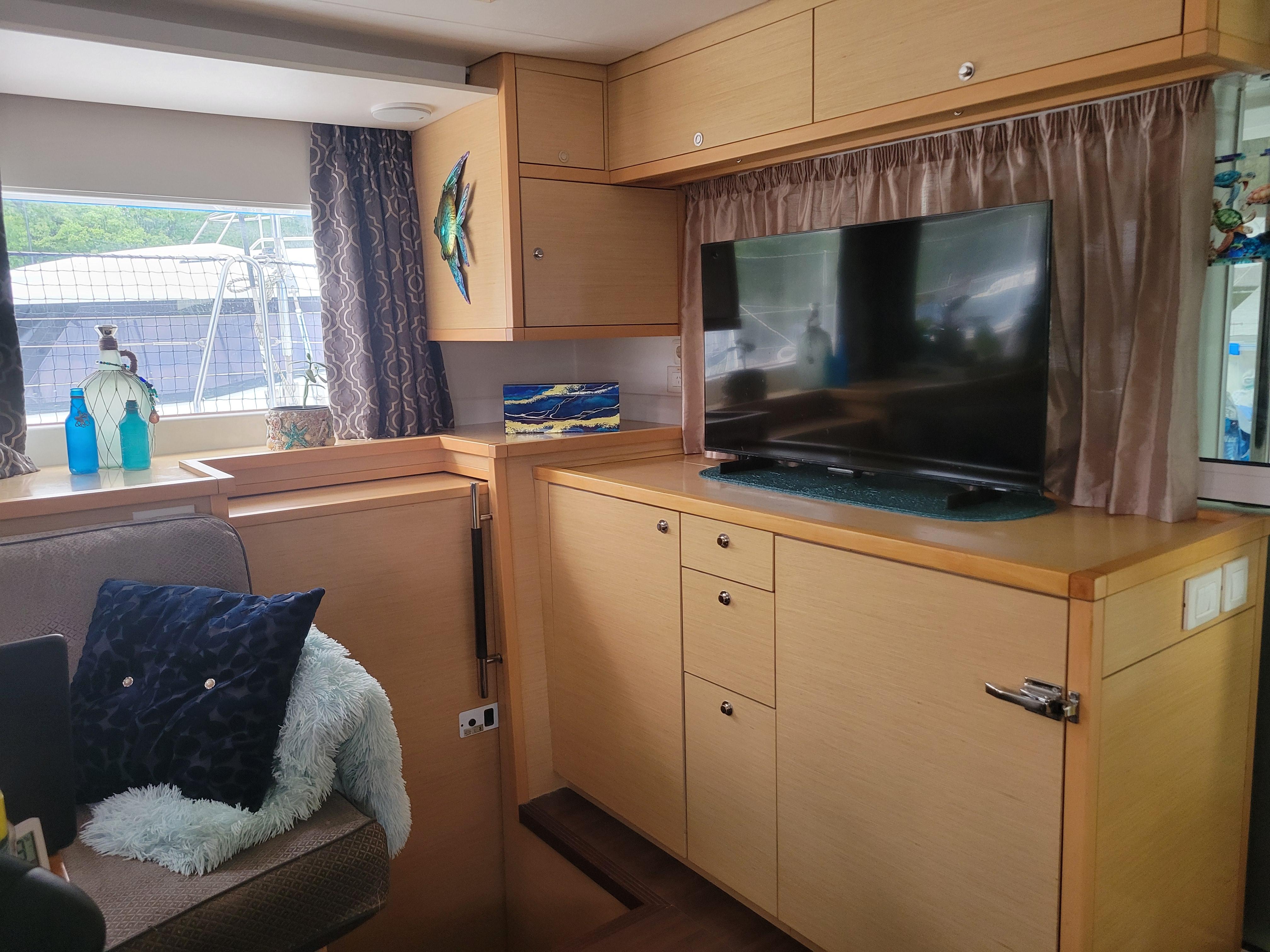 Interior of 2011 Lagoon 450 yacht with TV, cabinets, and cozy seating area.