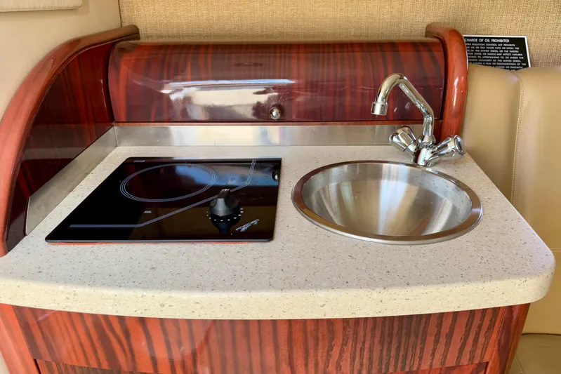  Yacht Photos Pics 2012 Cobalt 323 boat kitchenette with stove and sink, featuring wood accents.