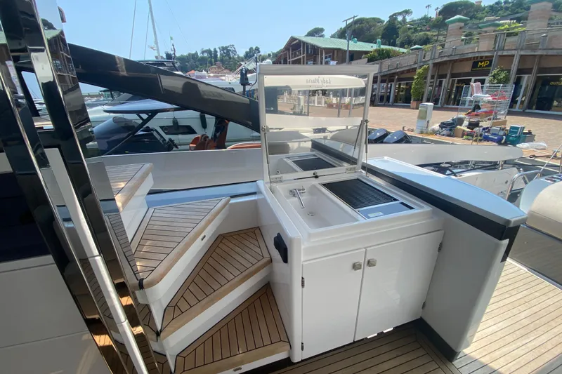  Yacht Photos Pics 2023 Azimut S7 yacht with outdoor kitchenette and teak steps in a marina setting.