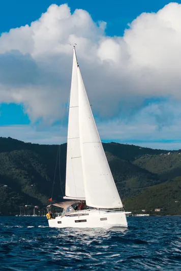 Easy Skanking Yacht Photos Pics 2024 Jeanneau Sun Odyssey 410 sailing on blue ocean with scenic mountain backdrop.