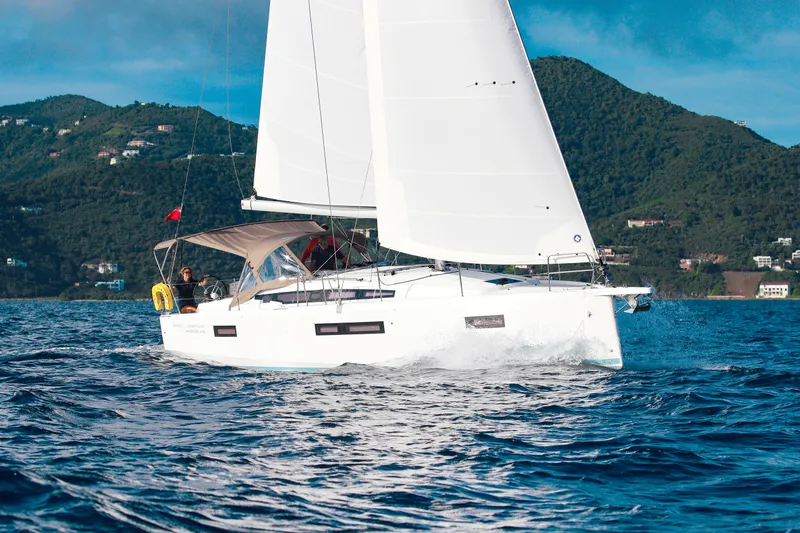 Easy Skanking Yacht Photos Pics 2024 Jeanneau Sun Odyssey 410 sailing near lush green hills.