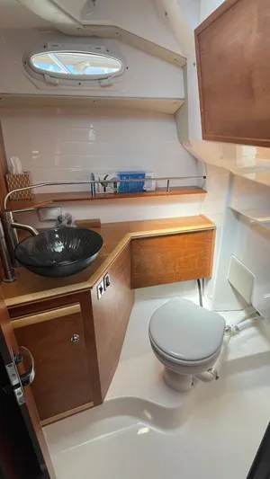  Yacht Photos Pics 2023 Cutwater C-288 boat bathroom with modern sink, toilet, and wooden cabinetry.