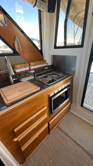  Yacht Photos Pics 2023 Cutwater C-288 boat kitchen with stove, oven, and wooden cabinetry.