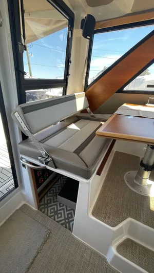  Yacht Photos Pics 2023 Cutwater C-288 interior with cushioned seating and wooden table, showcasing modern design.