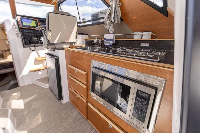  Yacht Photos Pics 2023 Cutwater C-288 boat interior with kitchen, featuring stove, microwave, and navigation area.