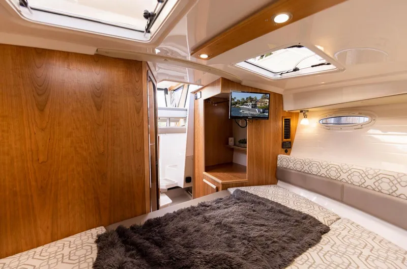  Yacht Photos Pics 2023 Cutwater C-288 interior cabin with cozy bedding, wood finish, and a mounted TV.