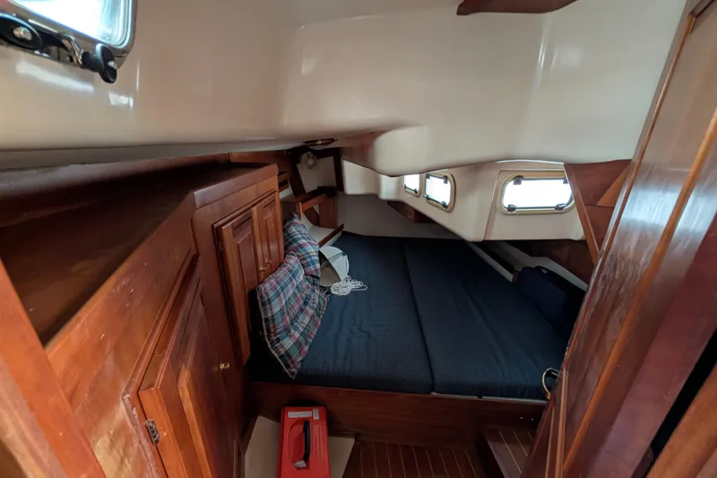 Thistle Yacht Photos Pics Cozy cabin interior of 2001 Tartan 3700 sailboat with wooden finishes and bedding.