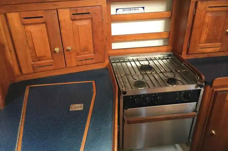 Thistle Yacht Photos Pics Wooden yacht kitchen with stove, cabinets, and blue countertops in a 2001 Tartan 3700.