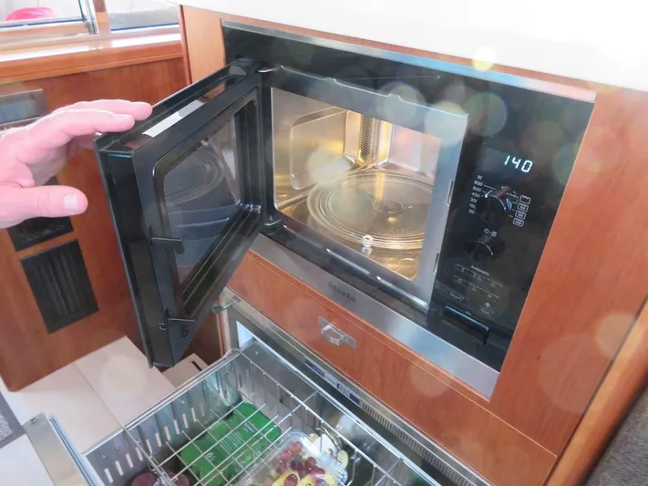  Yacht Photos Pics Microwave in Moody 54 DS yacht kitchen, door open, hand visible, modern design, 2018 model.