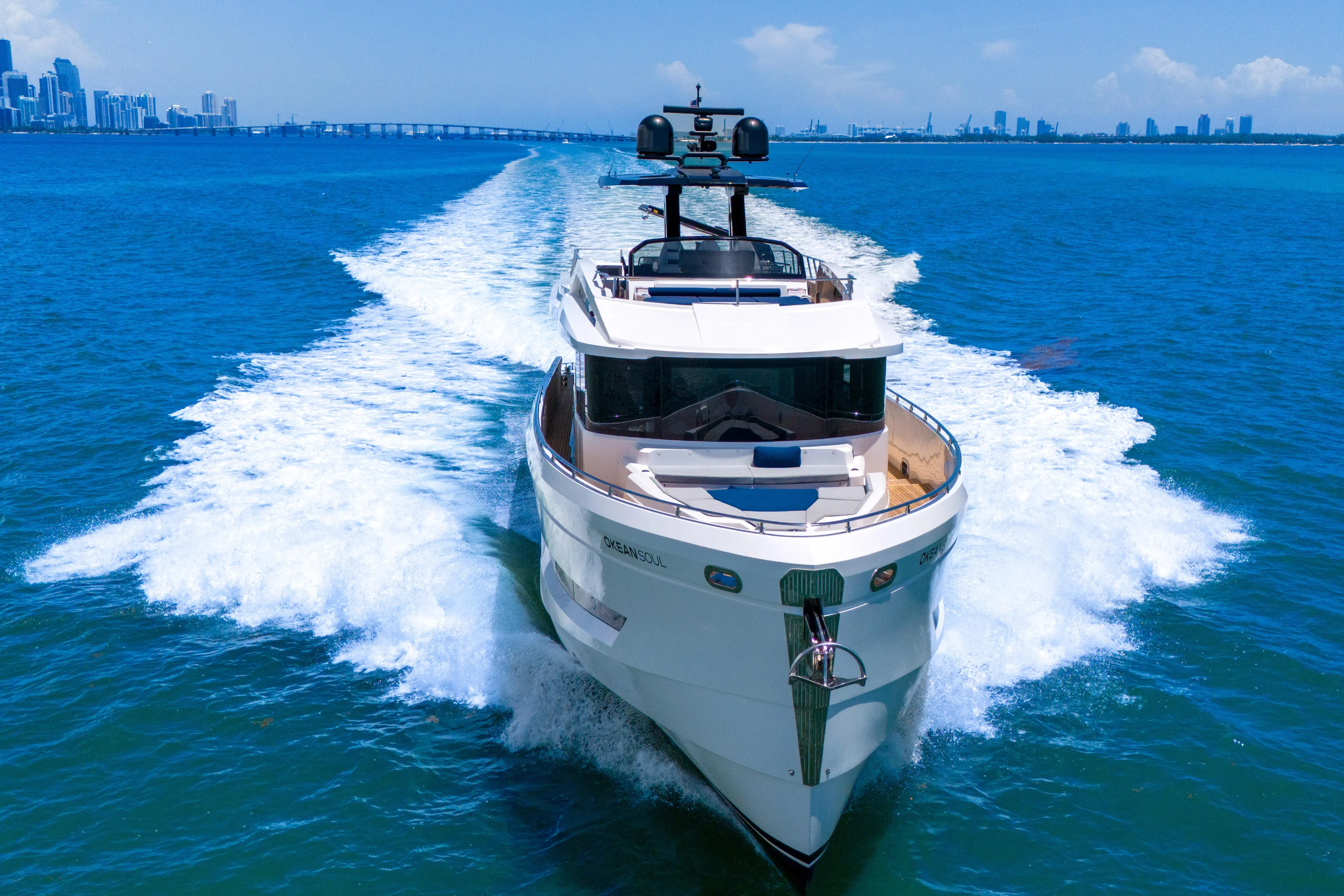  Yacht Photos Pics Luxurious 2021 OKEAN 80 yacht cruising in vibrant blue waters near a city skyline.